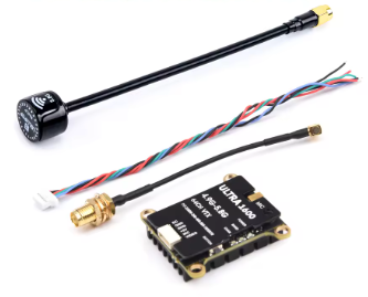 1.6W with 5.8G SMA Kleines schwarzes Funk-/Videomodul mit goldenen Montagebohrungen und Beschriftung, daneben gedrehte mehrfarbige Leitungen und zwei Anschlusskabel (eins mit goldener SMA-Buchse, eins mit weißem Steckverbinder) sowie eine lange schwarze Stabantenne mit rundem Sockel.