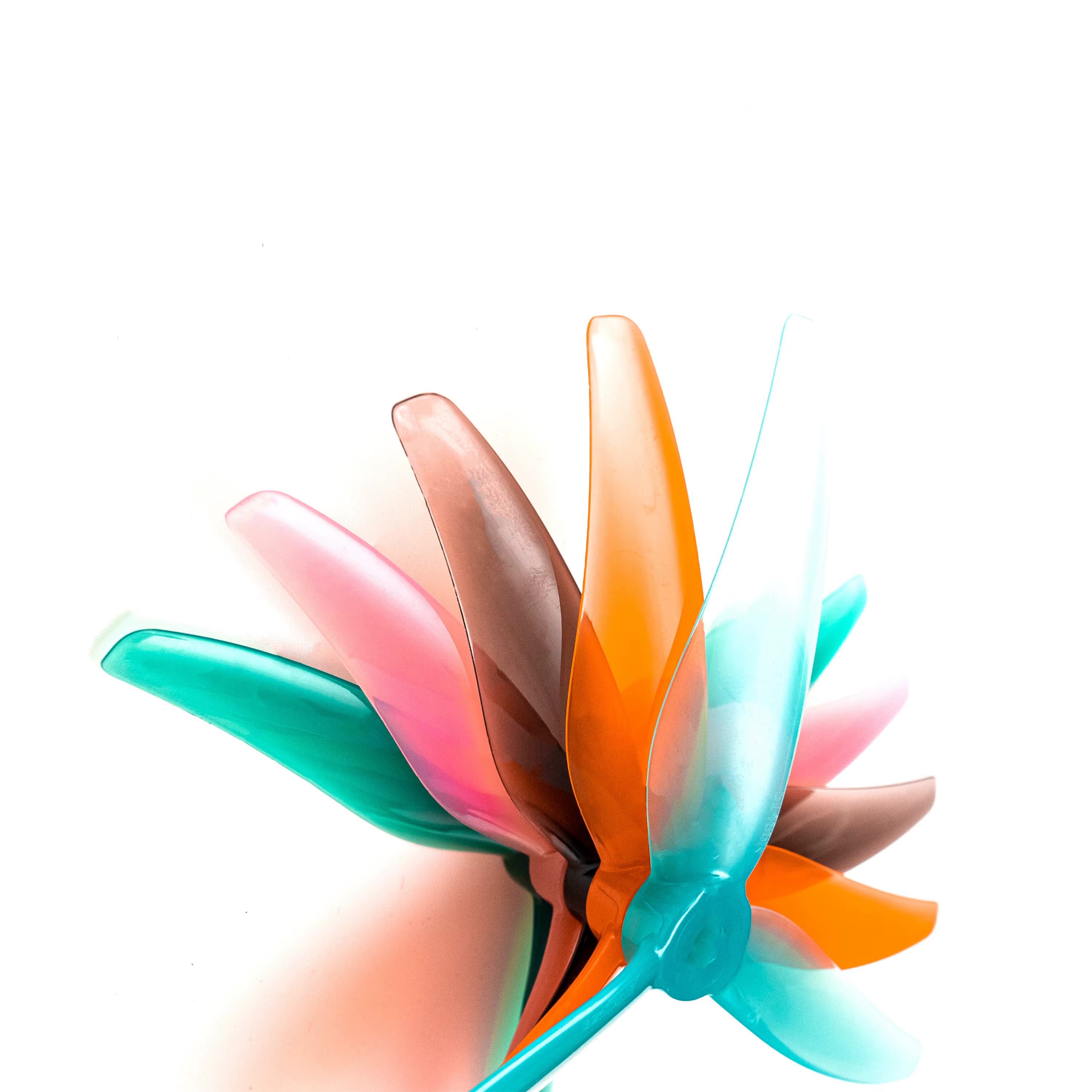 Mehrere halbtransparente 5‑Zoll‑FPV‑Drohnenpropeller mit je drei Blättern in Türkis, Orange, Rosa und Braun übereinander angeordnet vor weißem Hintergrund.
