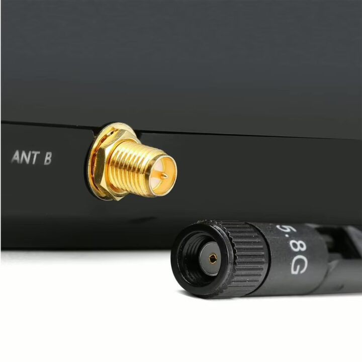 Nahaufnahme eines goldfarbenen SMA-Buchsenanschlusses an einem schwarzen Gerät mit der Beschriftung ANT B und des abgenommenen schwarzen Antennensteckers mit der Aufschrift 5.8G.