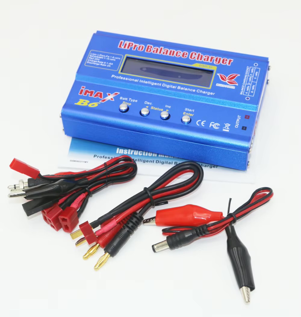 Blaues LiPro Balance Charger (iMAX B6) mit Display und vier silbernen Tasten, davor mehrere rote und schwarze Anschlusskabel mit goldenen Bananensteckern, roten Deans‑Steckern, Hohlstecker und Krokodilklemmen auf weißem Hintergrund.