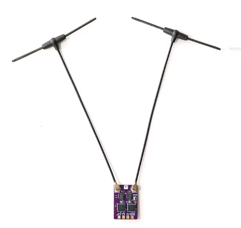 Kleine violette Leiterplatte mit sichtbaren elektronischen Bauteilen, an der zwei lange schwarze Antennenkabel in V‑Form befestigt sind, jeweils mit T‑förmigen Endstücken vor weißem Hintergrund.