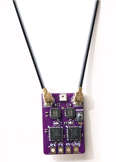 Kleine lila Leiterplatte mit vier quadratischen ICs, zwei goldenen Antennenbuchsen, an denen schwarze Antennenkabel angeschlossen sind, einem Boot-Taster und den Beschriftungen RX, TX, 5V und GND am unteren Rand.