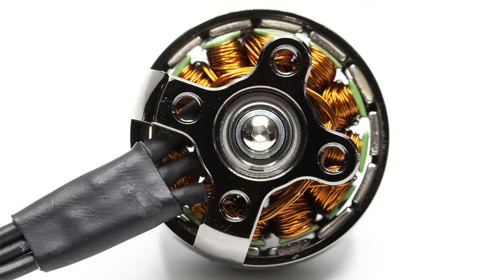 emax-eco-ii-2207-1900kv-motor-fpv-racing-drohne Nahaufnahme eines offenen FPV-Drohnen-Bürstenlosmotors auf weißem Hintergrund, mit glänzender Metallnabe, sichtbaren kupferfarbenen Wicklungen und drei schwarz isolierten Anschlusskabeln.