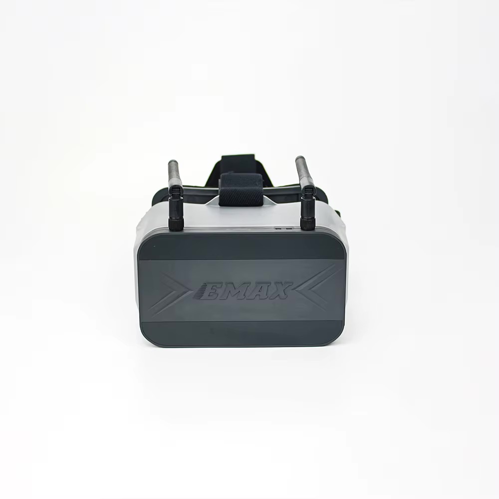 emax-transporter-2-43-zoll-fpv-brille-seitlich FPV-Brille mit dunkler Frontplatte mit EMAX-Logo, zwei aufgesetzten Antennen und schwarzem Kopfband vor hellem Hintergrund.