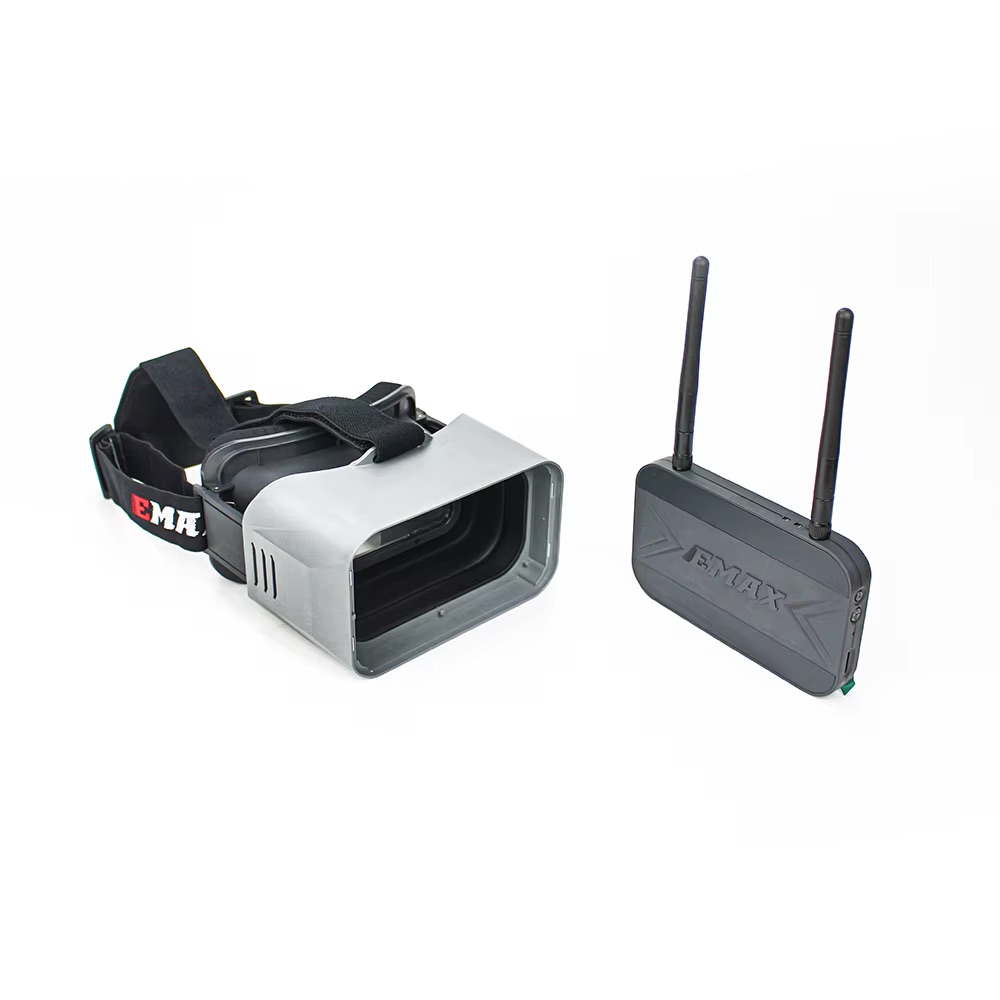 FPV-Brille mit grauem Sonnenschild, schwarzem Kopfband mit EMAX-Logo und dazugehörigem schwarzem Funkempfänger mit zwei Antennen.