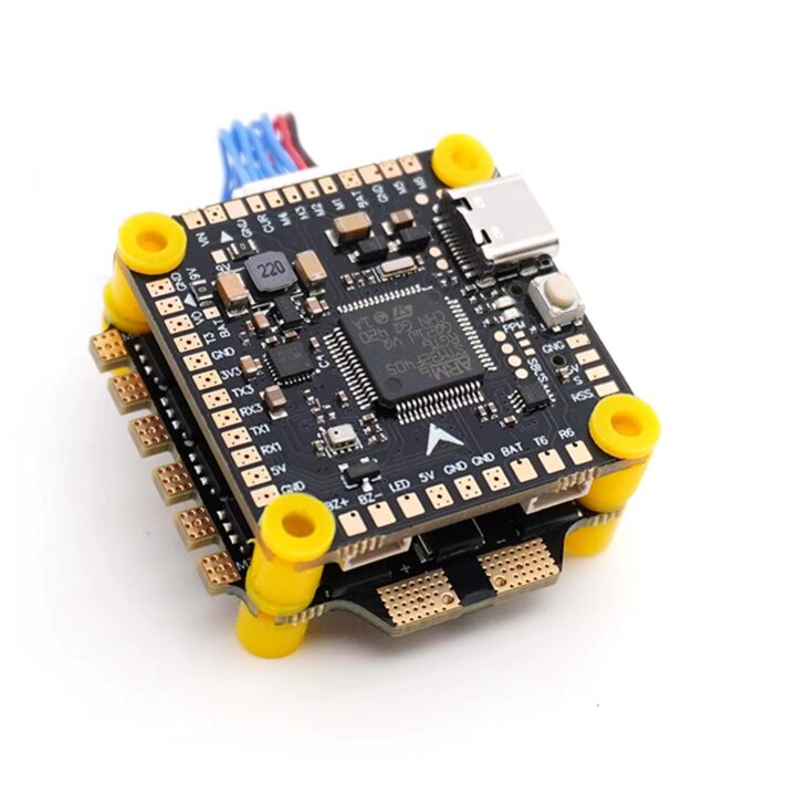Schwarzer Flight‑Controller für FPV‑Drohnen mit aufgelötetem Mikrocontroller, USB‑C‑Port, zahlreichen goldfarbenen Lötpads, gelben Abstandshaltern und gestapelter ESC‑Platine.