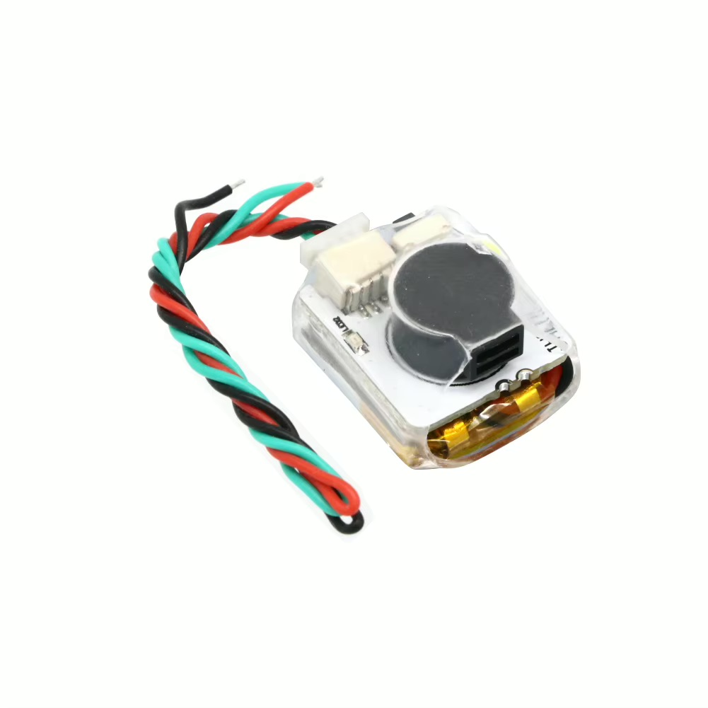 Kleines transparentes elektronisches Modul mit zwei runden schwarzen Bauteilen unter dem Gehäuse, sichtbarer goldfarbener Folienbatterie und verdrilltem Kabel in Rot, Grün und Schwarz auf weißem Hintergrund.