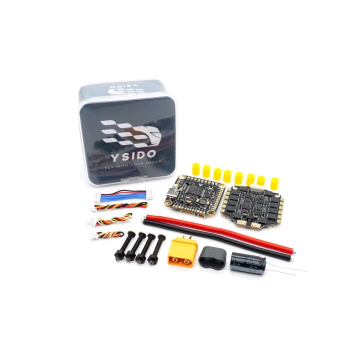 Nahaufnahme eines FPV-Flight-Controller-Kits: zwei elektronische Platinen (Flight Controller und ESC) neben bunten Anschlusskabeln, XT60-Stecker, Elektrolytkondensator, Schrauben, gelben Kabelhülsen und einer durchsichtigen Kunststoffbox mit YSIDO-Logo auf weißem Hintergrund.