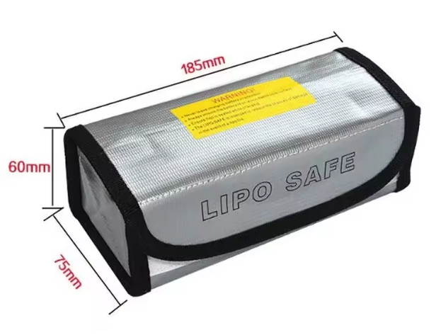 Silberne rechteckige LiPo-Sicherheitstasche mit schwarzem Saum, Aufdruck „LIPO SAFE“ vorne, gelbem Warnaufkleber auf der Oberseite und eingezeichneten Maßen 185 × 75 × 60 mm.