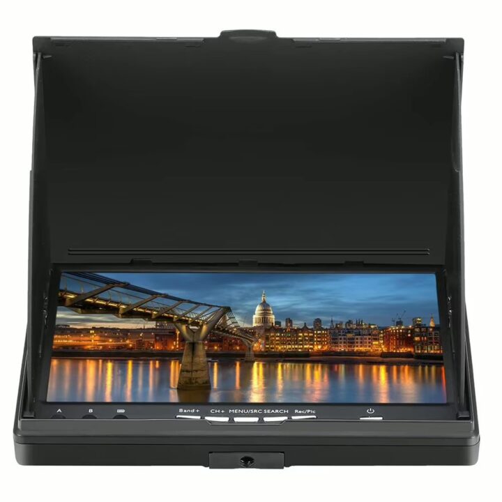 Klappbarer schwarzer LCD-Monitor mit Sonnenblende und Bedientasten, auf dem eine beleuchtete Stadt mit einer Fußgängerbrücke und ihren Lichterspiegelungen im Wasser bei Abenddämmerung zu sehen ist.