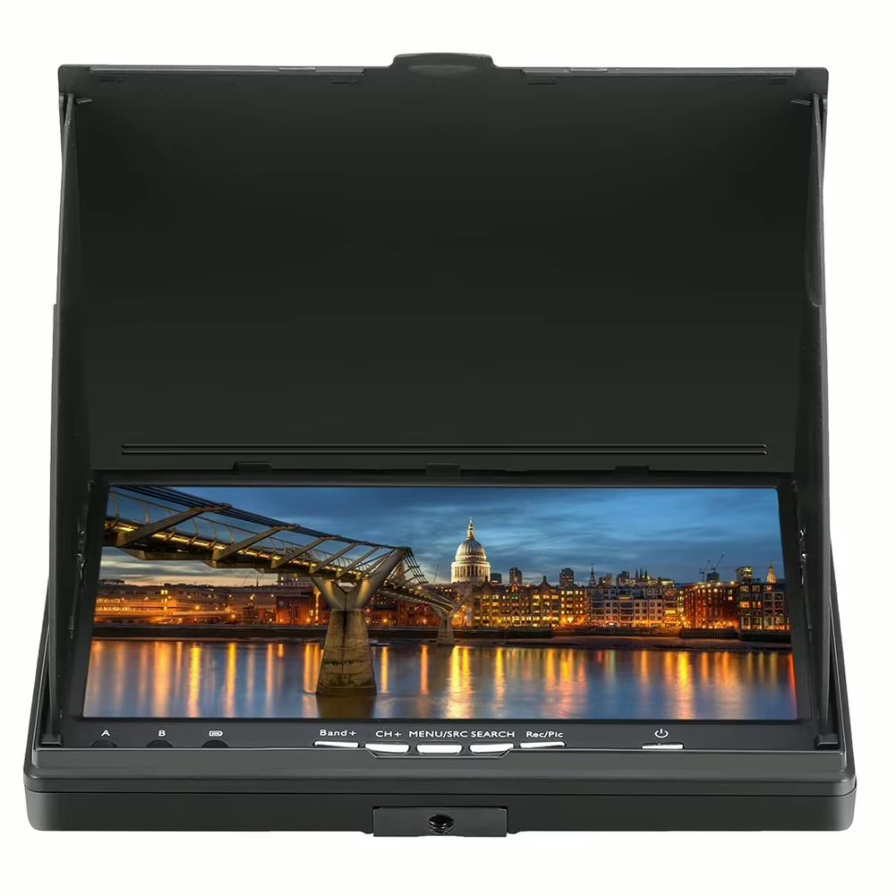 Klappbarer schwarzer LCD-Monitor mit Sonnenblende und Bedientasten, auf dem eine beleuchtete Stadt mit einer Fußgängerbrücke und ihren Lichterspiegelungen im Wasser bei Abenddämmerung zu sehen ist.