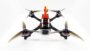 Frontansicht einer FPV-Renn-Drohne auf weißem Hintergrund mit roter Cockpit-Verkleidung, sichtbarer Kamera, vier Carbon-Armen und vier 5-Zoll-Dreiblatt-Propellern mit lila Motorhauben.