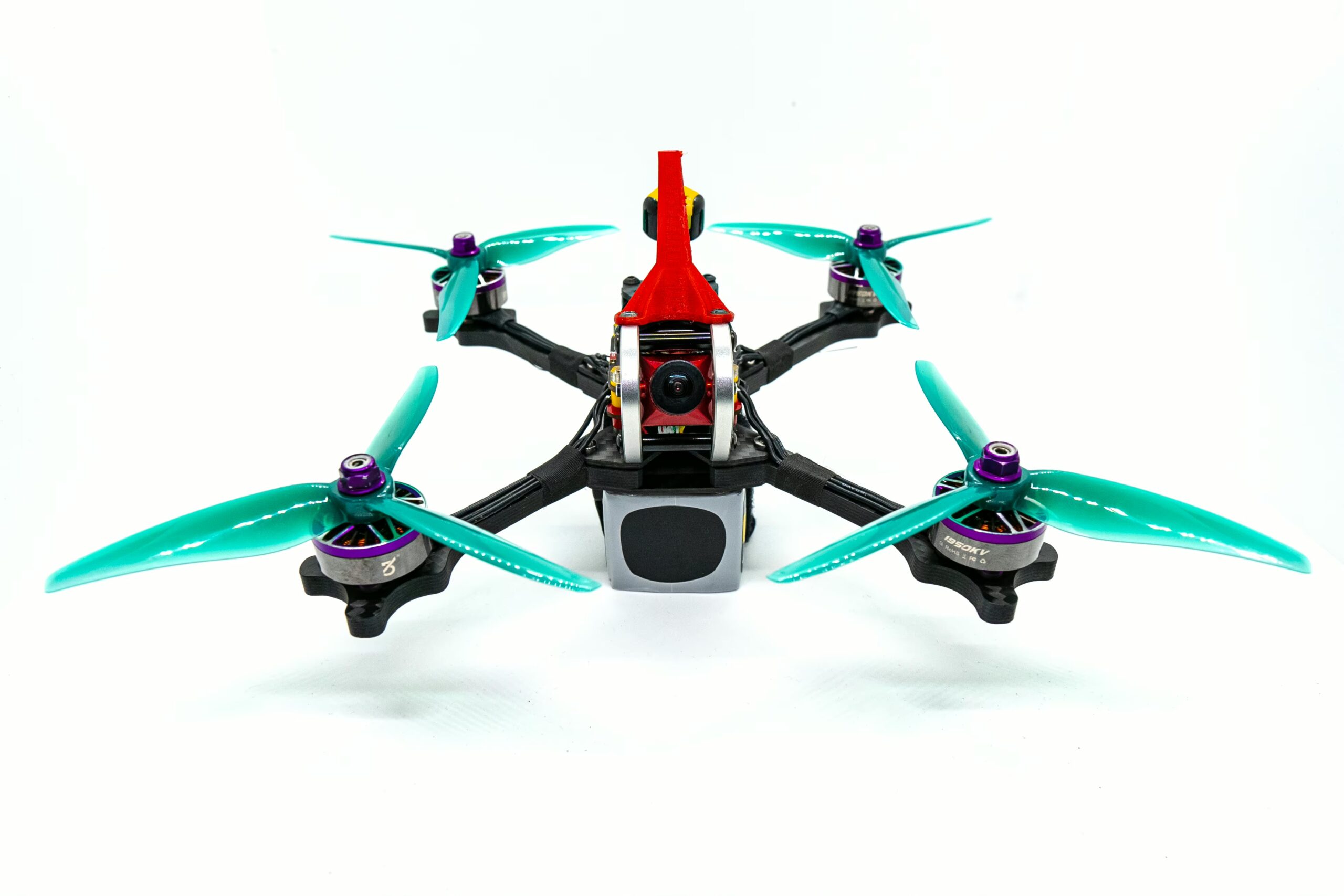Viermotoriger FPV-Racing-Quad mit leuchtend türkisfarbenen 5-Zoll-dreiblättrigen Propellern, roter Verkleidung, schwarzen Carbon-Armen, lila Motorhülsen und vorn sichtbarer FPV-Kamera vor weißem Hintergrund.