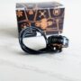 Schwarz glänzender FPV-Drohnen-Brushless-Motor mit sichtbarer Aufschrift EX1404, aufgewickeltem Anschlusskabel und im Vordergrund vor einer schwarz-orangen Verpackung auf hellem Untergrund.