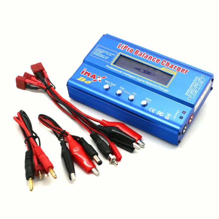 Blaues iMax B6 LiPo-Balance-Ladegerät mit LCD-Display und vier Bedienknöpfen, dazu mehrere rote und schwarze Anschlusskabel, Krokodilklemmen und Stecker auf weißem Hintergrund.