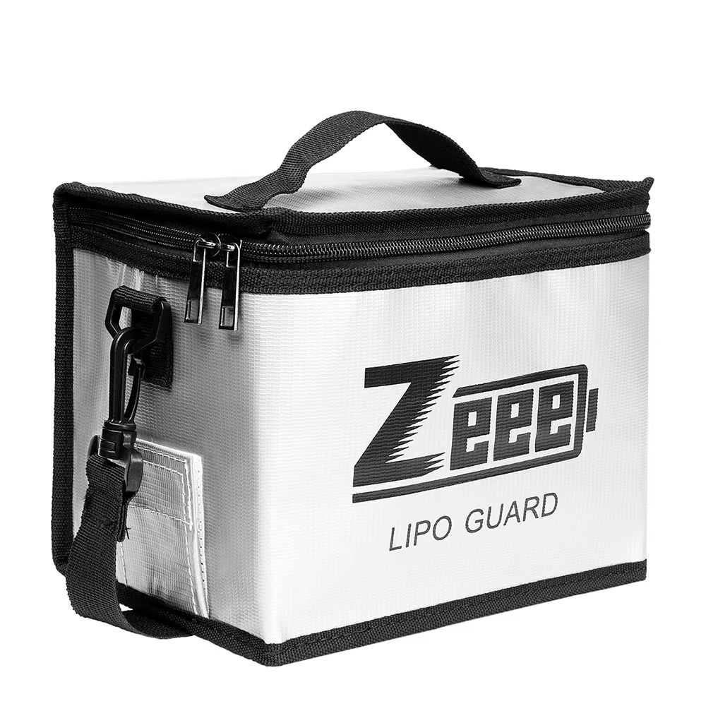 Weiße, rechteckige Lipo-Schutztasche mit schwarzem Reißverschluss und Rand, kleinem Tragegriff oben, abnehmbarem Schulterriemen mit Clip und aufgedrucktem "Zeee! LIPO GUARD"-Logo.