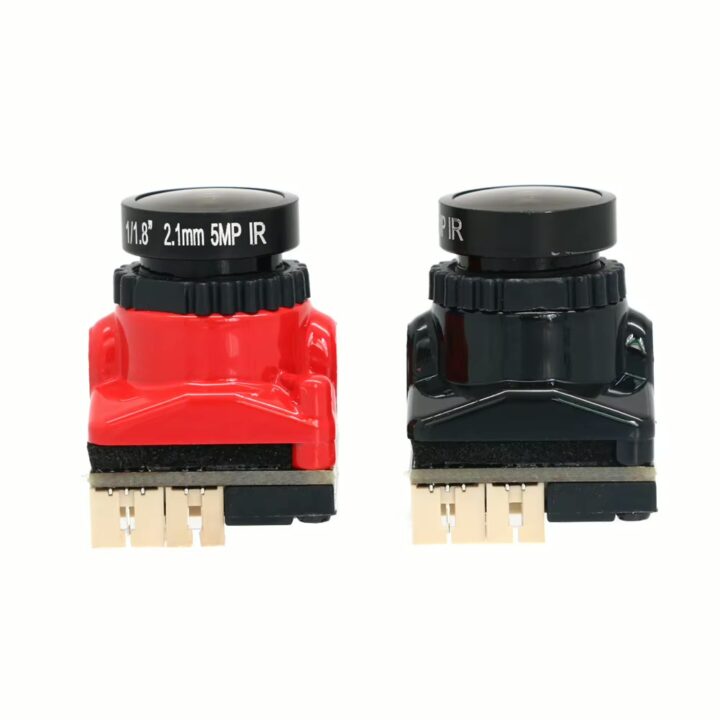 mini-fpv-kamera-25x19mm-fuer-rc-drohne Zwei kompakte Boardkameramodule nebeneinander auf weißem Hintergrund — links rotes, rechts schwarzes Gehäuse, jeweils rundes Objektiv mit Beschriftung oben und sichtbaren Steckverbinderpins an der Unterseite.